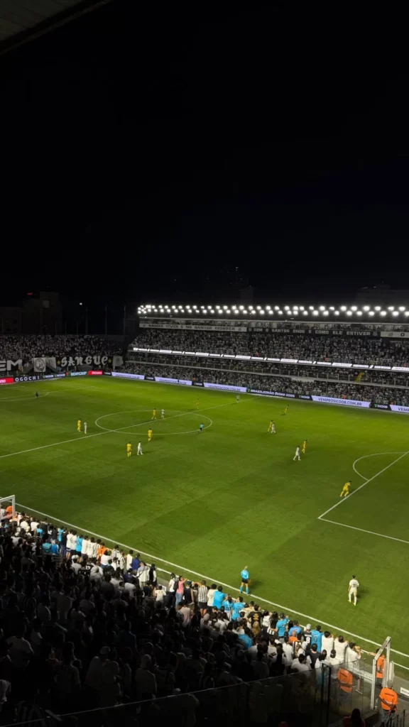 Campo da Vila Belmiro durante a partida entre Santos e Mirassol, com jogadores em campo e arquibancadas cheias
