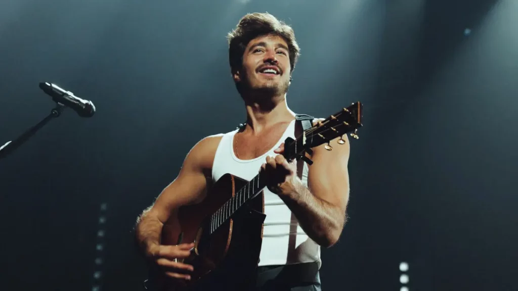 Tiago Iorc toca violão durante apresentação em show.