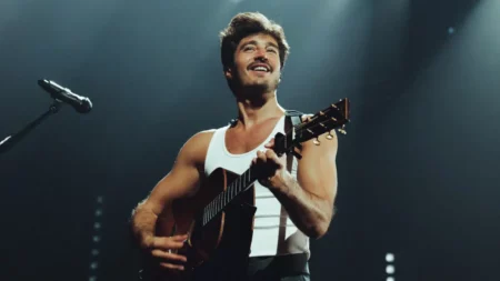 Tiago Iorc toca violão durante apresentação em show.