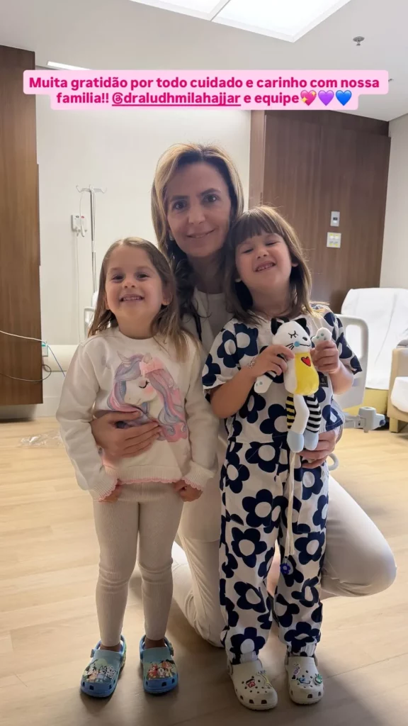 Filhas de Virginia Fonseca, Maria Alice e Maria Flor, posam sorridentes com médica no hospital após cirurgia