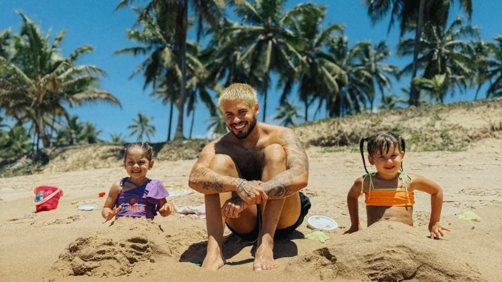 Zé Felipe revela motivo para filhas seguirem em São Paulo após cirurgia; veja Zé Felipe aparece sorrindo ao lado das filhas, Maria Alice e Maria Flor, durante um momento em família na praia.