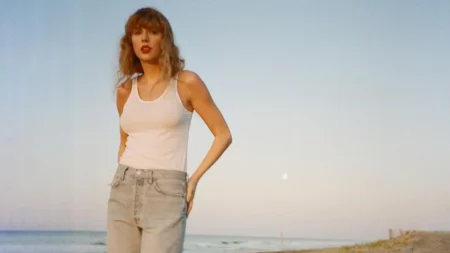 Taylor Swift posa à beira-mar usando regata branca e calça jeans.