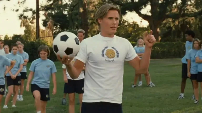 Erik von Detten segura uma bola de futebol durante treino esportivo ao ar livre, cercado por jovens uniformizados, em cena do filme O Diário da Princesa.