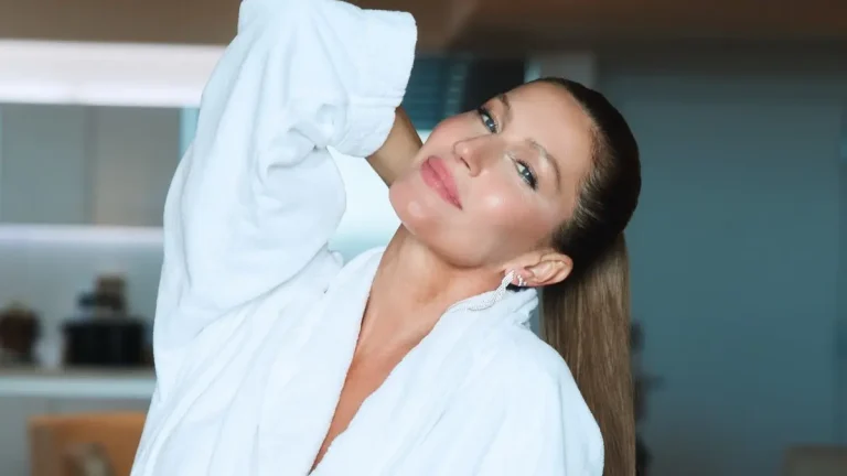 Gisele Bündchen posa com roupão branco, cabelo preso em rabo de cavalo e maquiagem leve.