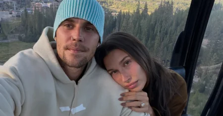 Justin Bieber troca palco por plateia e fãs fazem cobrança; entenda Justin Bieber, de gorro azul e moletom claro, posa ao lado de Hailey Bieber dentro de um teleférico, com uma paisagem montanhosa ao fundo