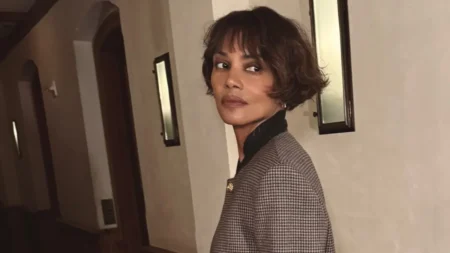 Halle Berry posa com cabelo curto castanho e blazer xadrez em ambiente interno.