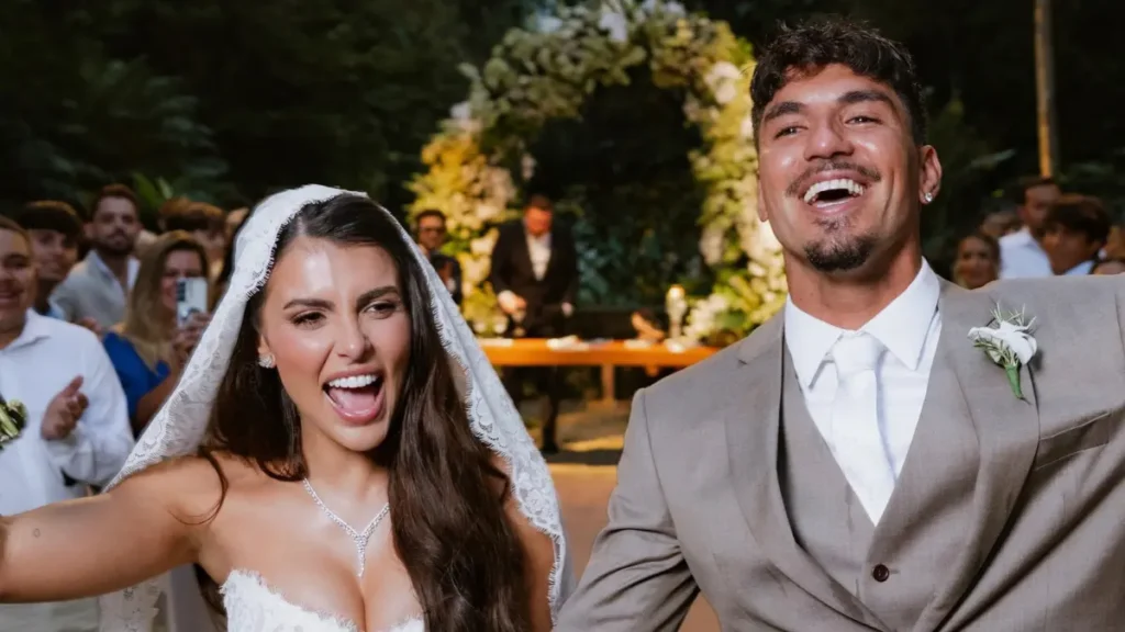Isabella Arantes e Gabriel Medina aparecem sorrindo durante a cerimônia de casamento, realizada em meio à natureza.