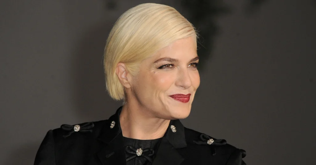 Selma Blair teria ficado sem medicação antes de confusão em voo, diz defesa Selma Blair sorri com cabelos loiros curtos, batom vermelho e roupa preta diante de um fundo escuro