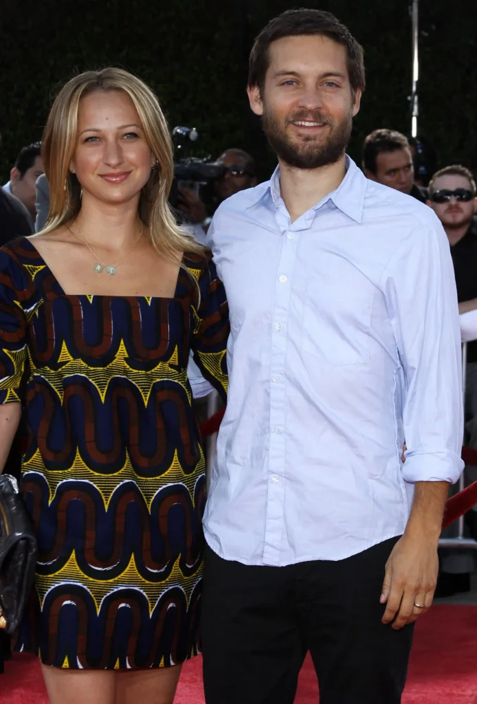Tobey Maguire casa a ex-mulher com herdeiro bilionário; entenda 3 Jennifer Meyer usa vestido estampado ao lado de Tobey Maguire, que veste camisa azul-clara, durante evento com tapete vermelho