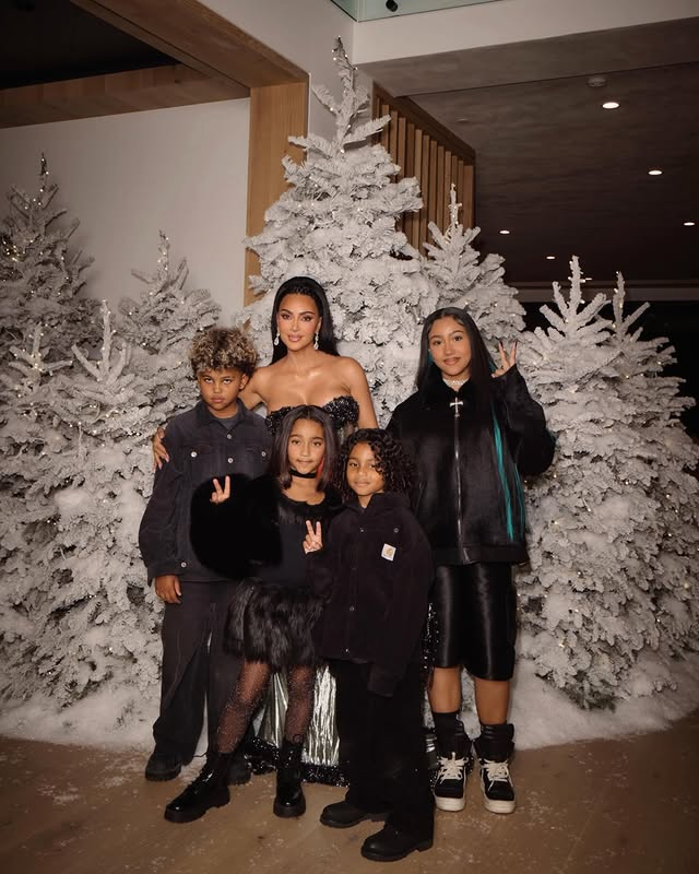 Virginia Fonseca, Ludmilla e Mariah Carey: 9 momentos do Natal de 2025 8 Kim Kardashian posa ao lado dos quatro filhos em frente a árvores de Natal decoradas em tons claros, durante celebração natalina em família.